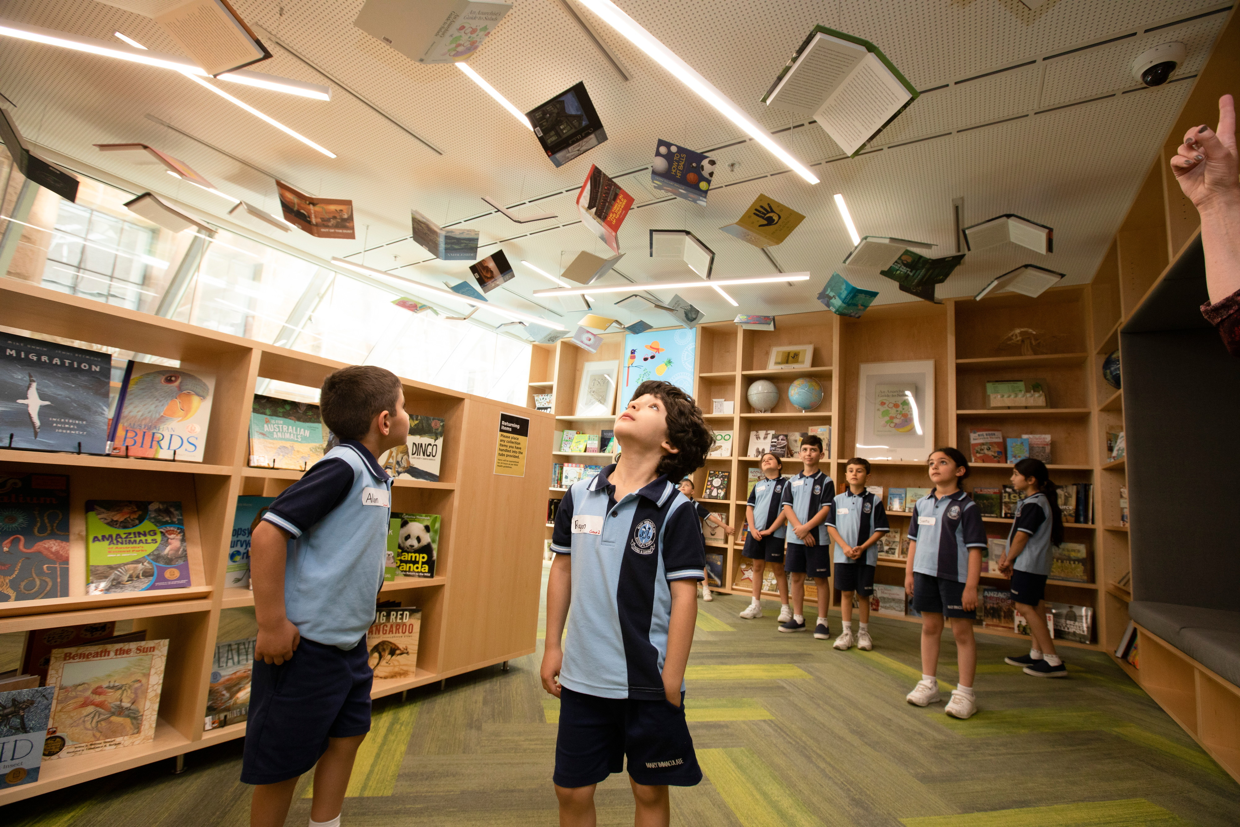Students look up at book covers hanging from the ceiling