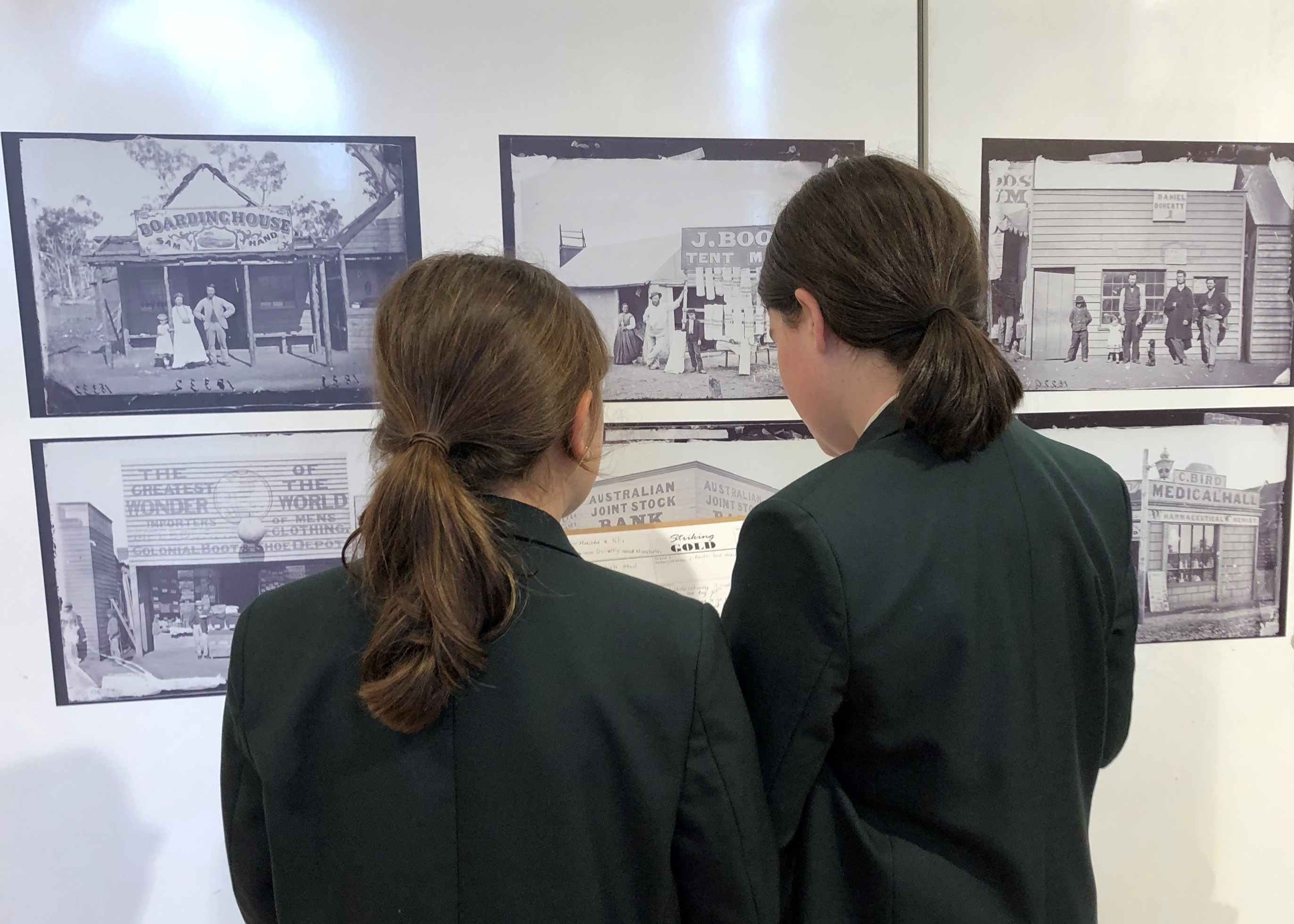 Two students looking at photographs taken of the goldfields in the 1872 as part of the Holtermann Collection