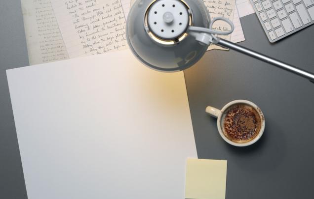 Coffee cup and pen and hand written paper under a lamp