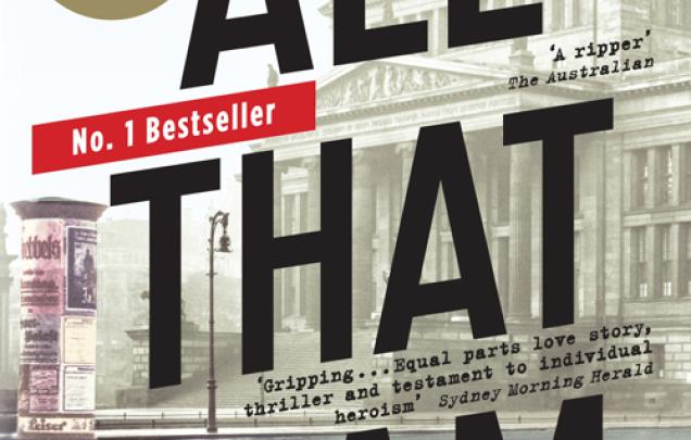 Woman in a street wearing a long coat facing a large historic old building for book cover of All That I am by Anna Funder