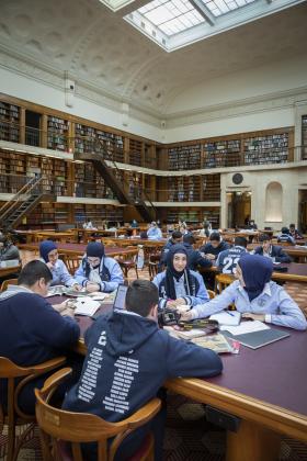 Group of students sitting around a table in library reading room