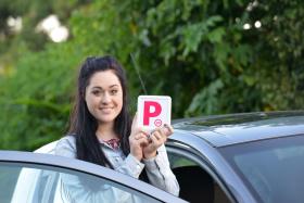 Young woman holding provisional plate next to car