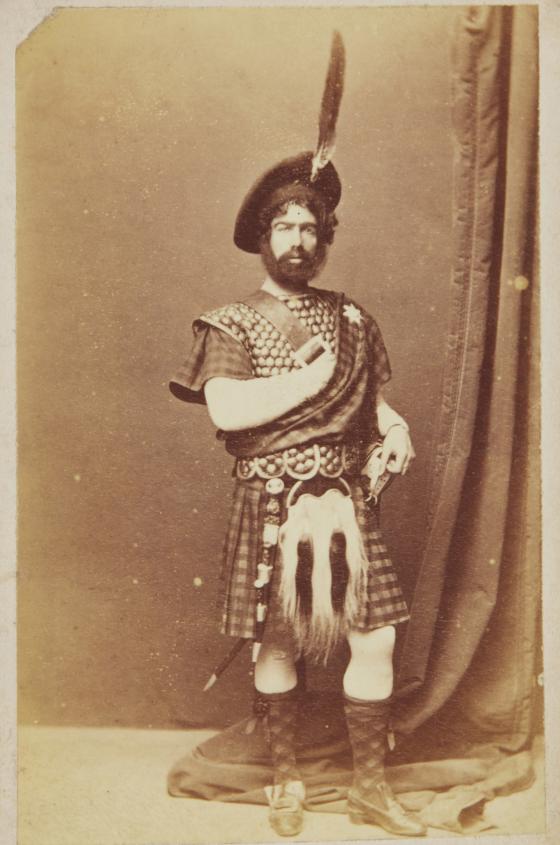 Sepia portrait of a man in kilt and hat.