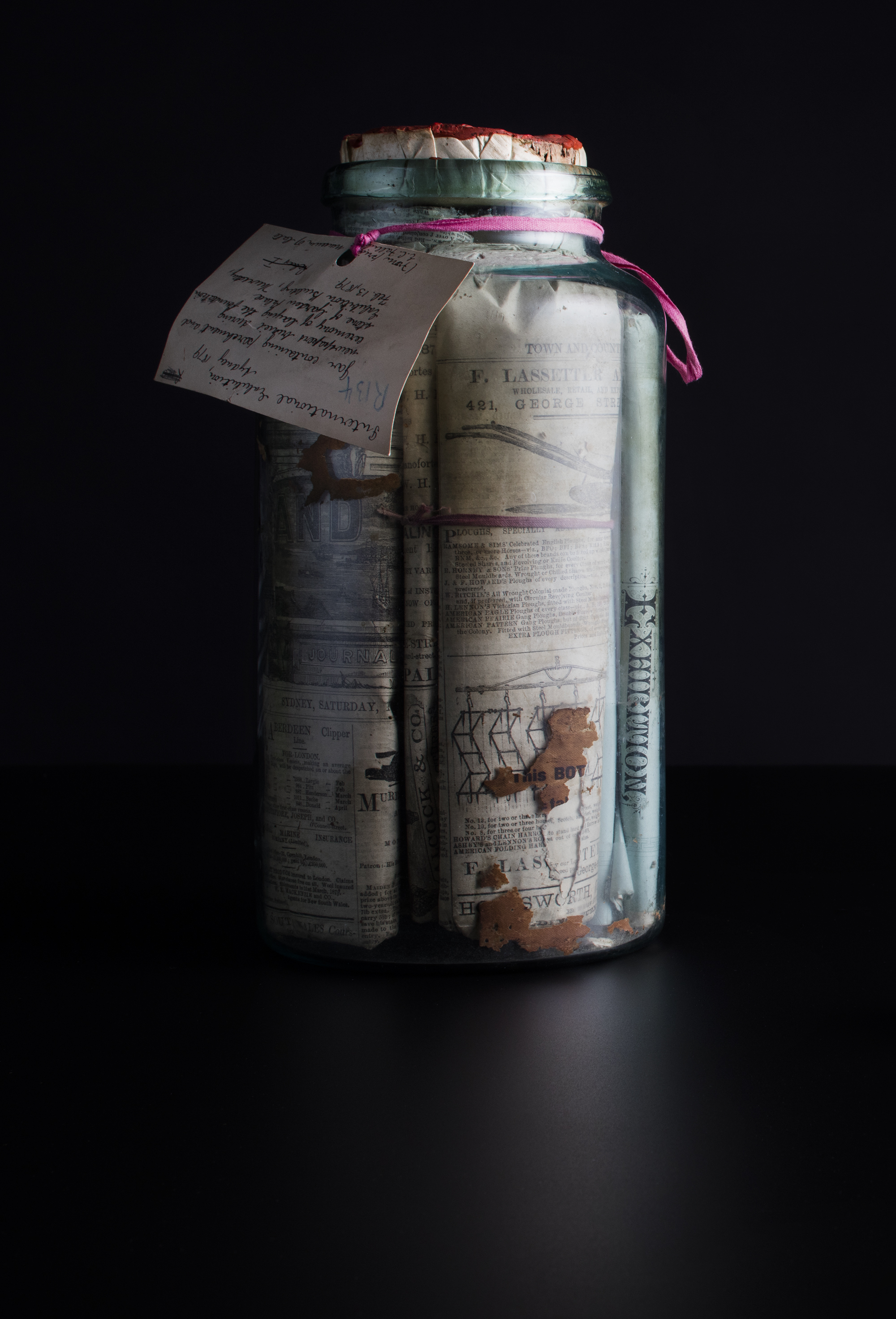 Glass jar filled with parchment and newspapers with cork stopper and red wax seal