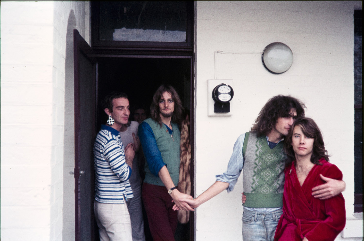 Colour photograph of four people standing at the front door of a house.