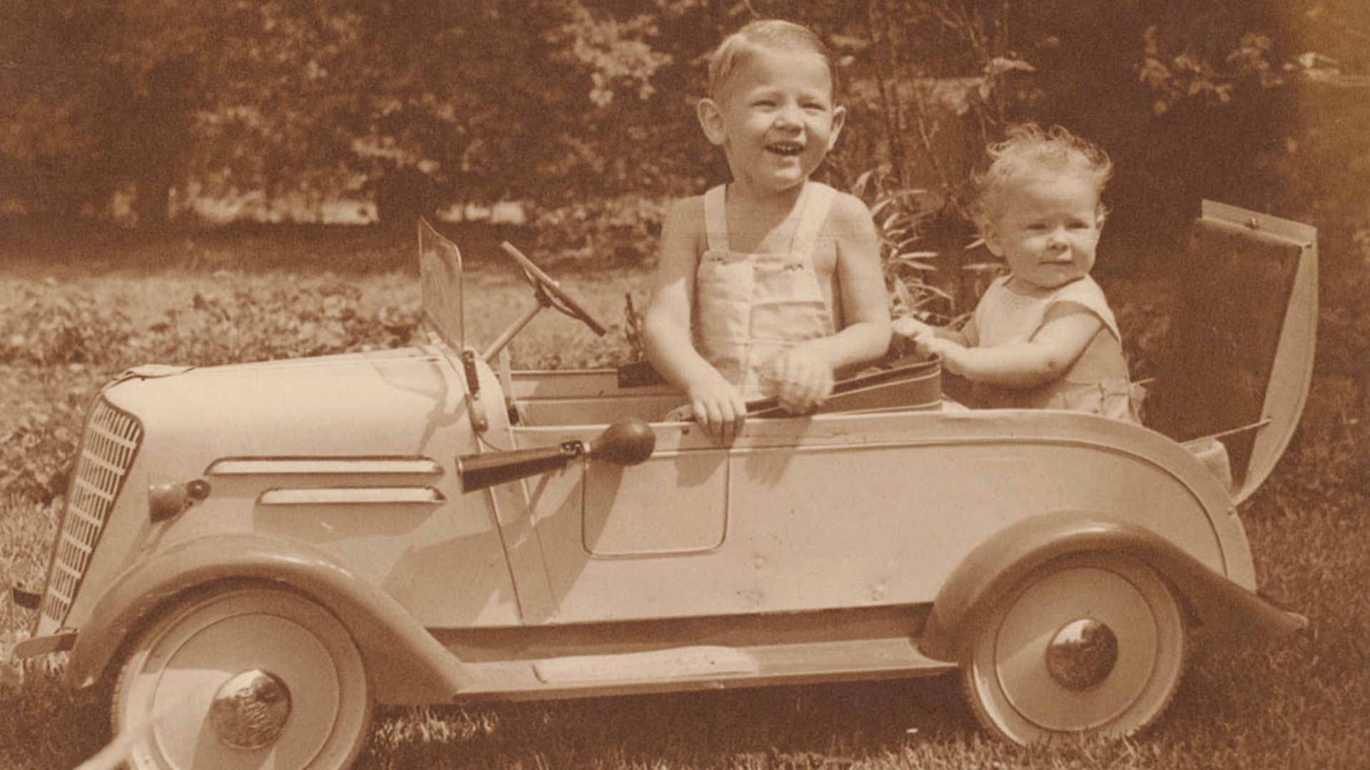 Two children sitting in a toy car