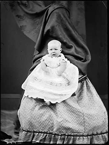 Alice Grotefent held by her mother Jane (behind curtain.) Holtermann negative G 359, box 15.