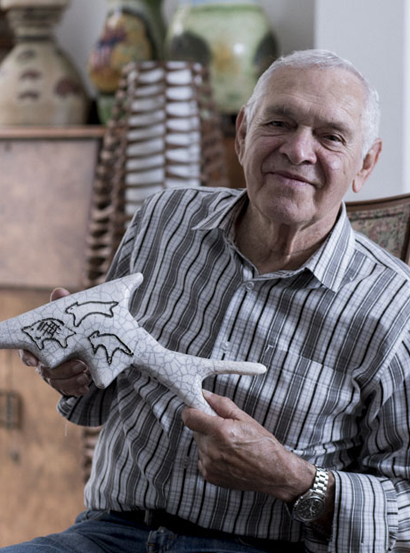 Portrait of a smiling man holding a ceramic fish.