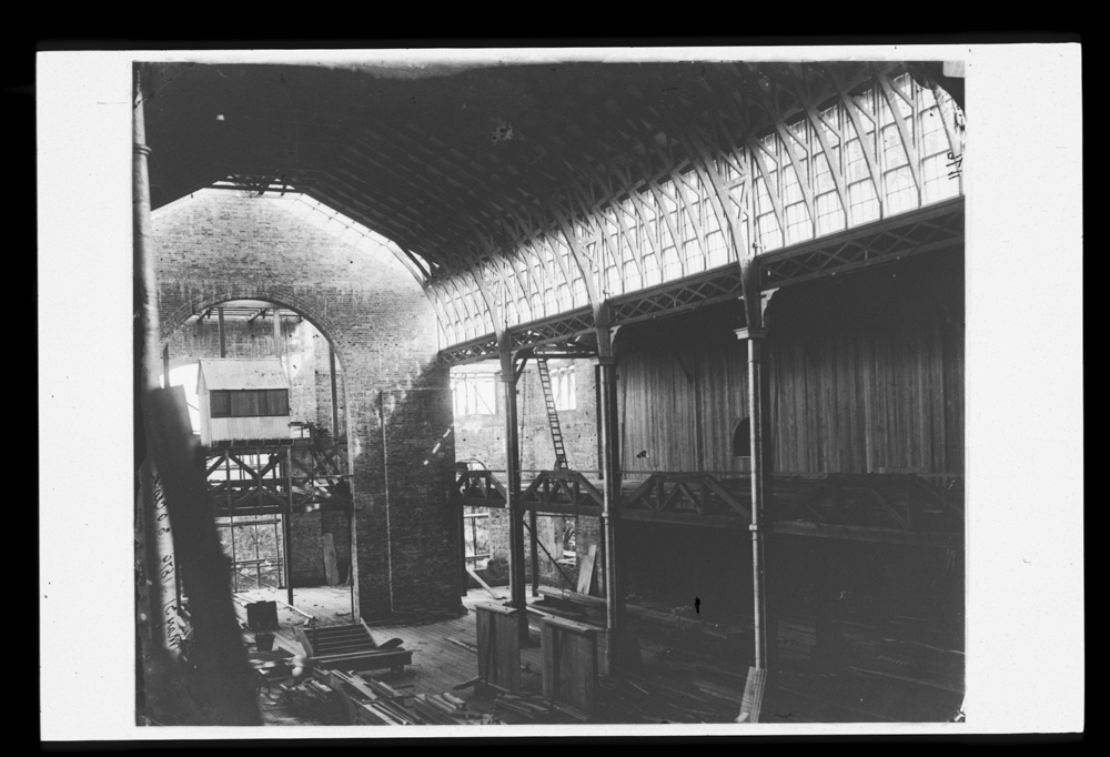Interior of the Garden Palace Sydney during construction, showing high brick wall and wooden beams