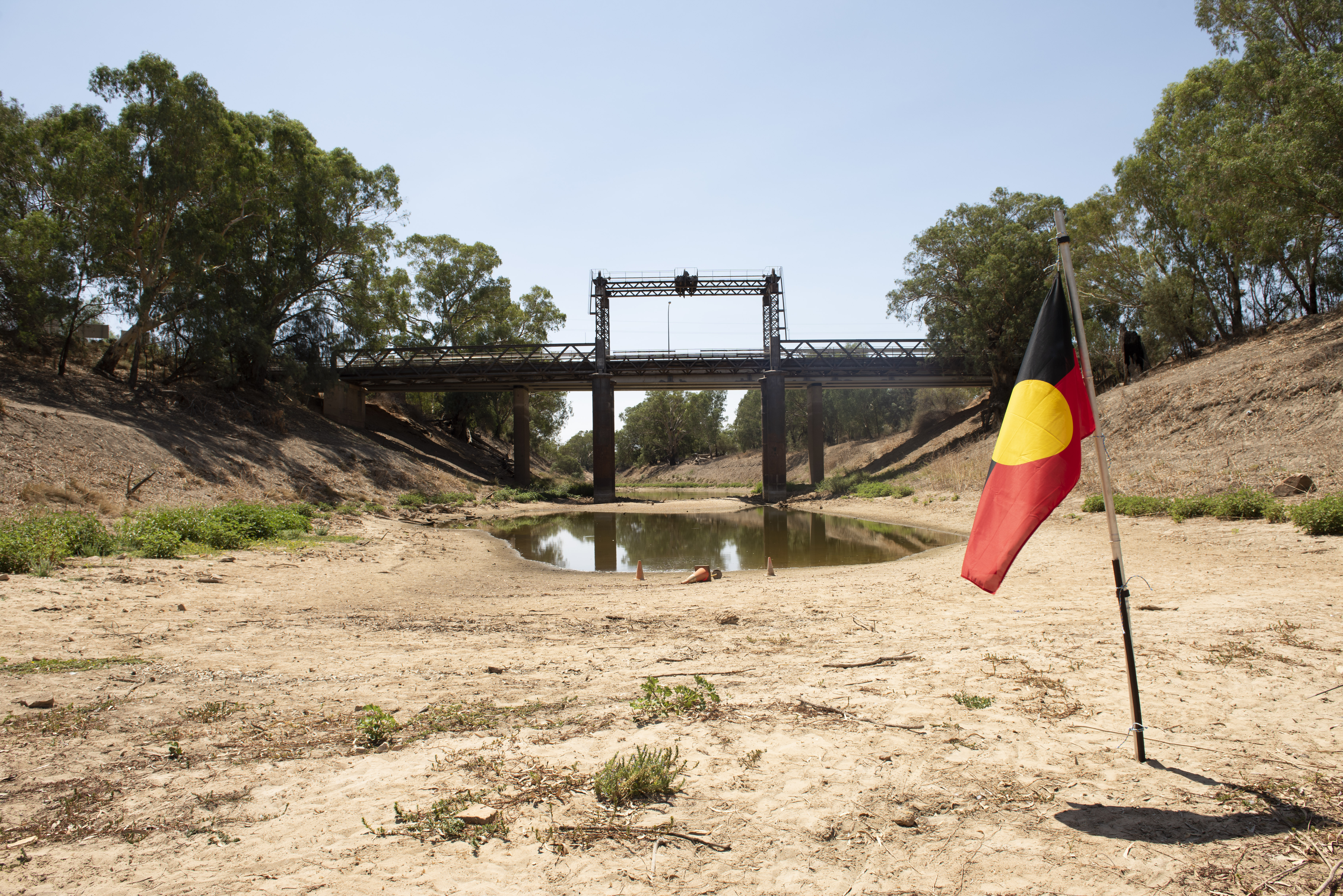 An Aboriginal flag is planted in a dry riverbed 