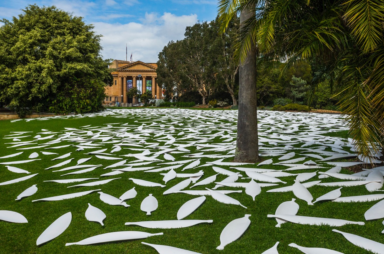 White ceramic shields on green grass at Royal Botanic Gardens with State Library of New South Wales in background