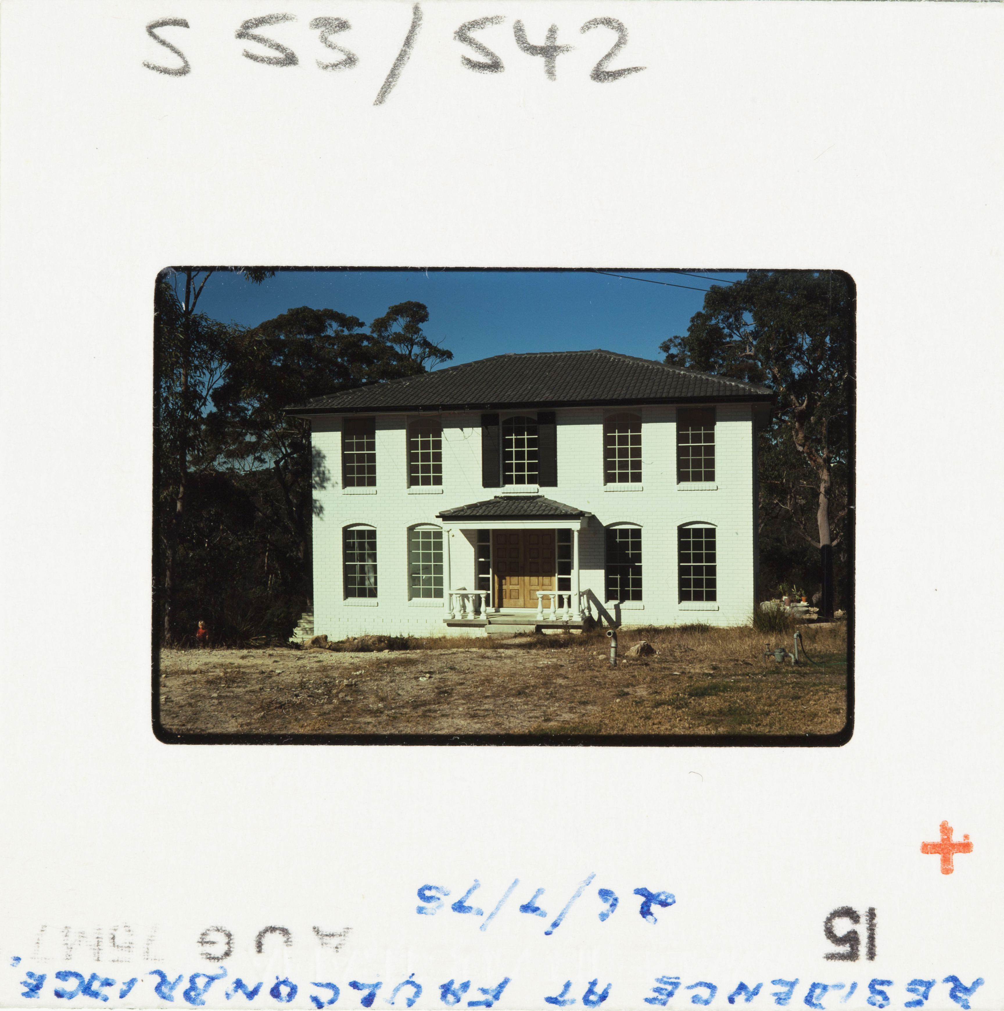 A 70s Kodak colour slide; a white brick house newly built with dry, grassless front yard.