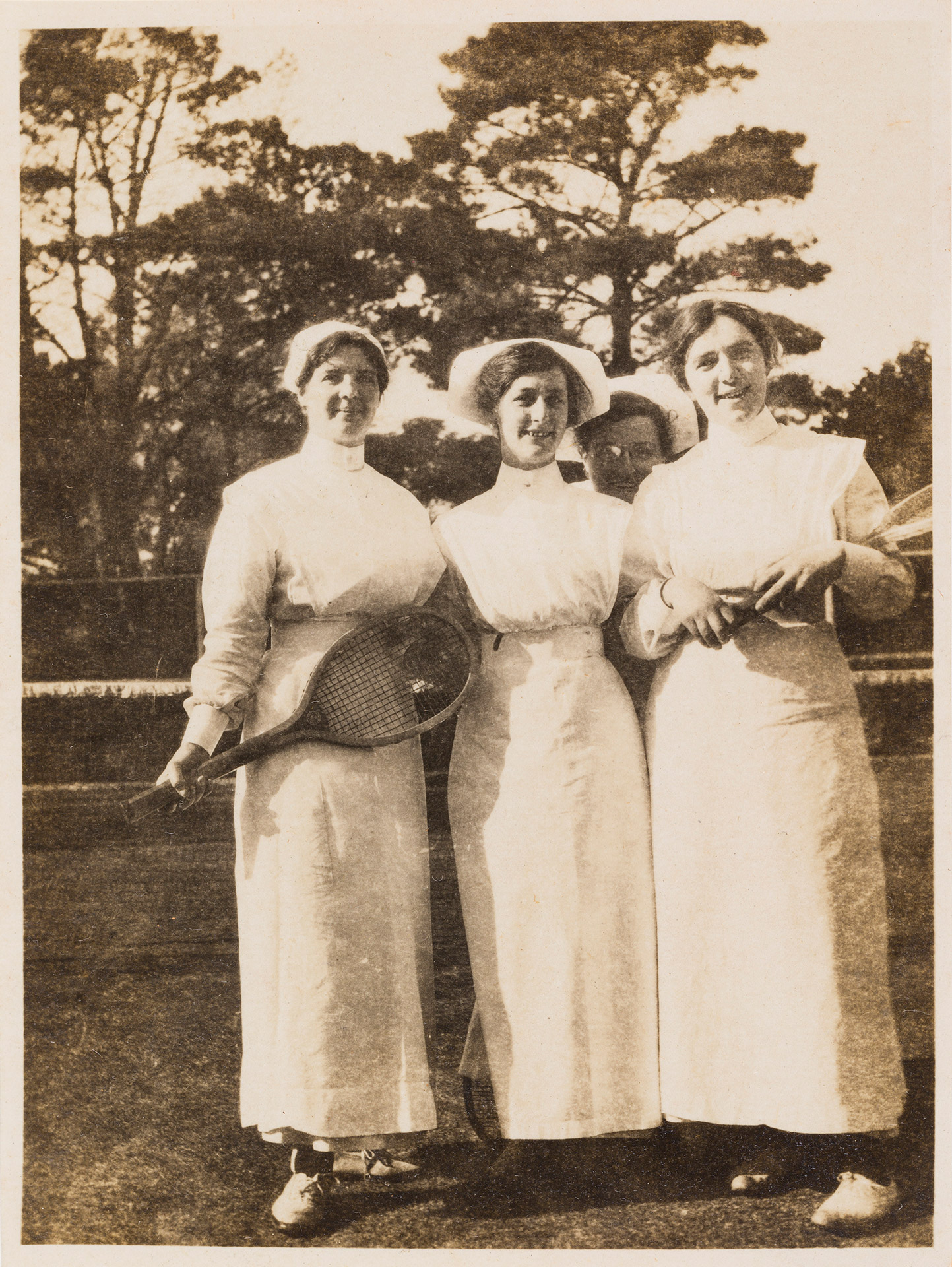 A sepia photograph depicting four women in nurse uniform standing together.