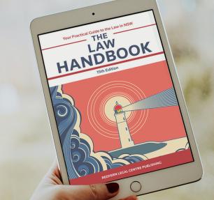 A hand holding an ipad with an image of the law handbook cover