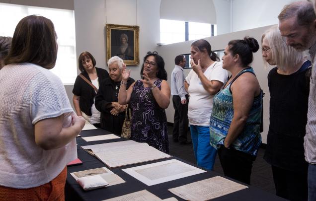 Group of people looking at manuscripts on a table 