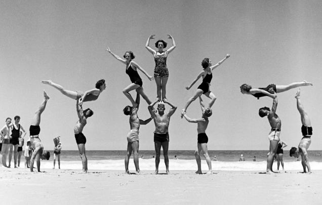 Group of people practicing gymnastics at the beach