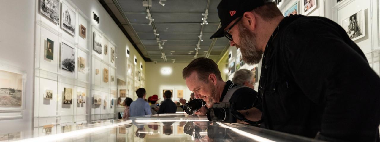 Two men looking at the display case in the Shot exhibition