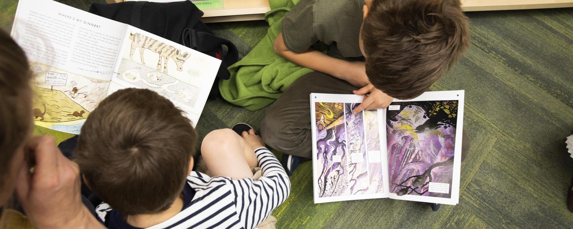 Two children reading books in library