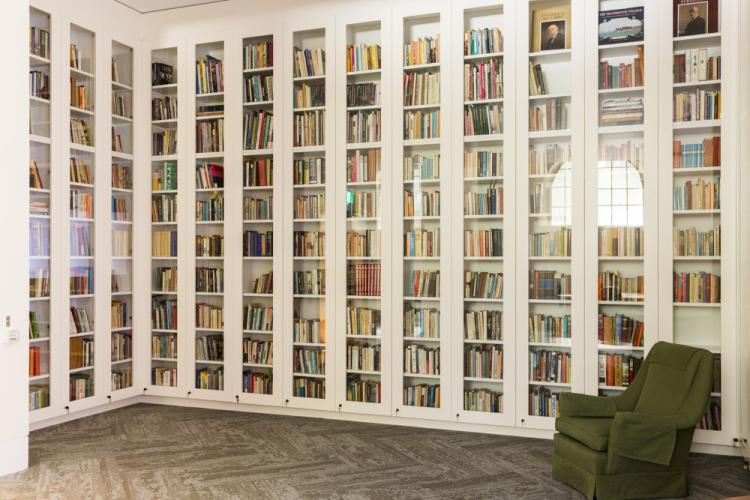 Modern bookcase lined with books and green chair