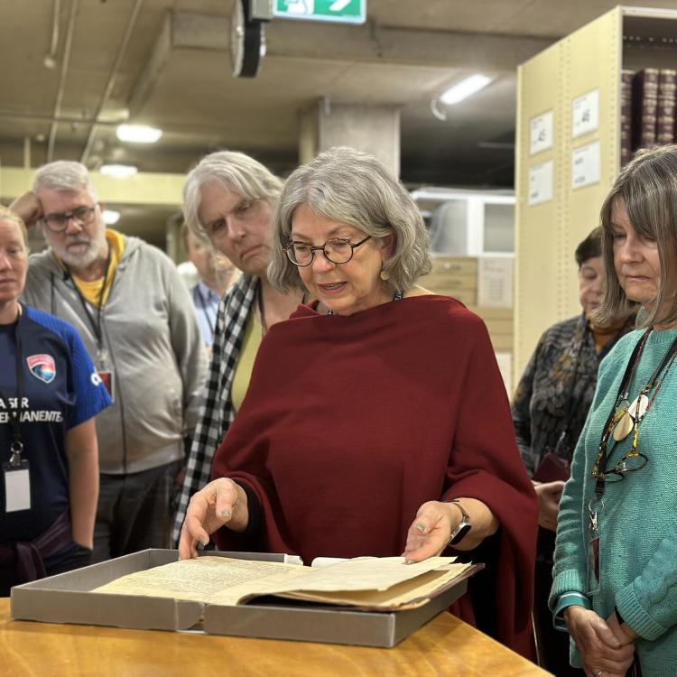 A person discusses a large book to a group of onlookers