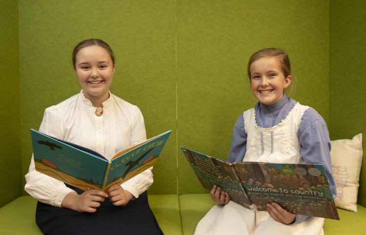 Two girls in costume reading books