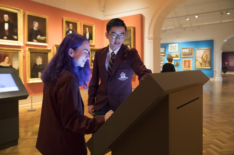 Two high school students looking at a computer screen display inside the Paintings from the Collection gallery