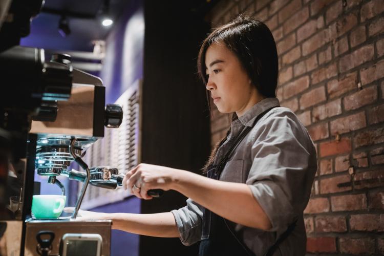 Young woman making coffee in a cafe