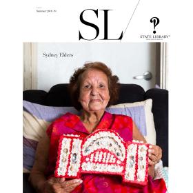 Magazine cover of an older woman proudly showing her crafted handiwork made of shells.