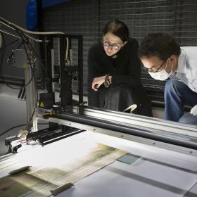 Man and woman looking at paper being digitised