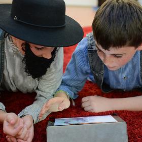 Two students looking at laptops dressed in period costume