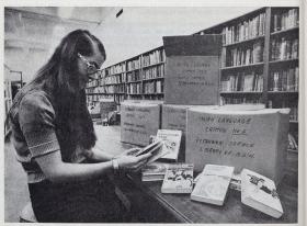 Woman sitting at a desk with boxes and books