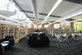 Internal view of library with lounges, tables and chairs and bookshelves