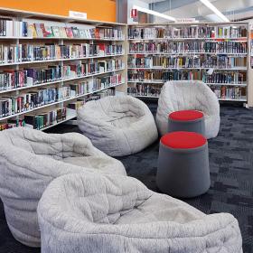 Three bean bag style chairs next to the Teen Fiction and Sci-Fi &amp; Fantasy shelves in a library.