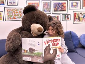 Child and teddy bear reading a book
