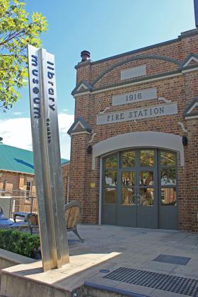A sign displaying the label "Library Museum" in front of a repurposed fire station building.