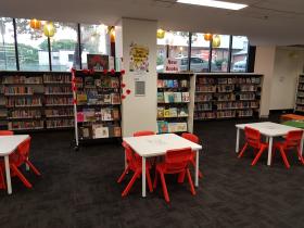 Children's area in library with tables and colourful chairs and bookshelves
