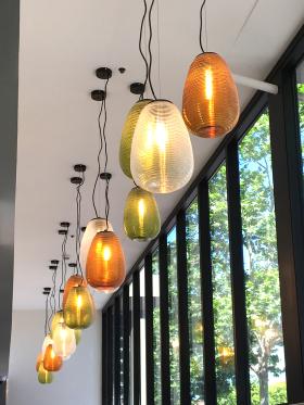 A number of pendant lights hanging from the ceiling with windows behind