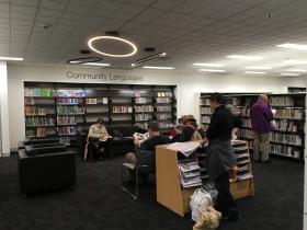 Bookshelves and seating in a library with people seated and standing