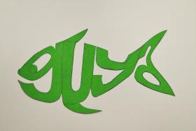 The word guya drawn in the shape of a fish on green cardboard