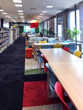 Long view of library bookshelves, tables and chairs