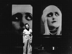 Black and white photograph of woman standing on stage.