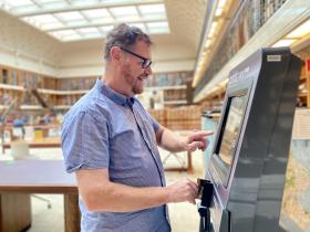Man using Library copy card reload kiosks in Mitchell Reading Room 