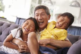 Grandfather hugging and laughing with two young granddaughters