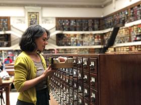 A woman in a green cardigan looking at index cards in the Mitchell Library Reading Room