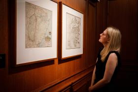 Woman looks at map on wall in State Library of NSW Map Rooms.
