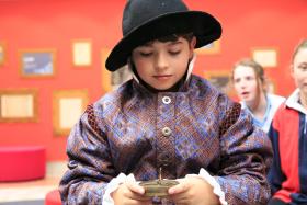 boy dressed in shakespearean costume looking down at a compass