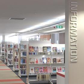 Library shelves with signs for information, great reads and large print