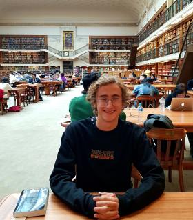 Photo of Will sitting in the Mitchell Library Reading Room.