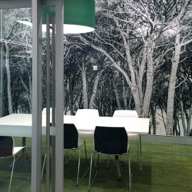 Glass fronted room with table and chairs and tree images on wall