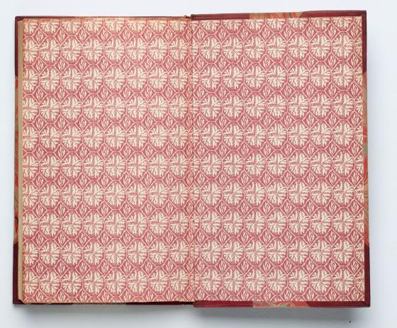 Endpapers with a repeating red floral pattern.